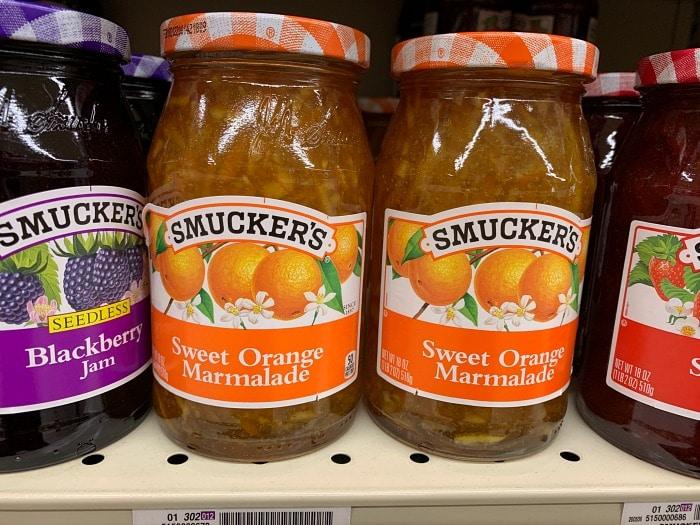 Jars of Smuckers Sweet Orange Marmalade sit on a store shelf, perfect for enhancing your favorite orange chicken recipe