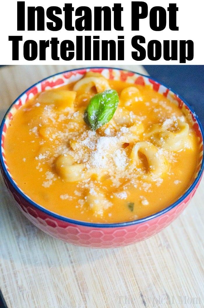 Bowl of creamy tortellini soup topped with grated cheese and basil, on a wooden surface—perfect for fans of instant pot soup recipes.