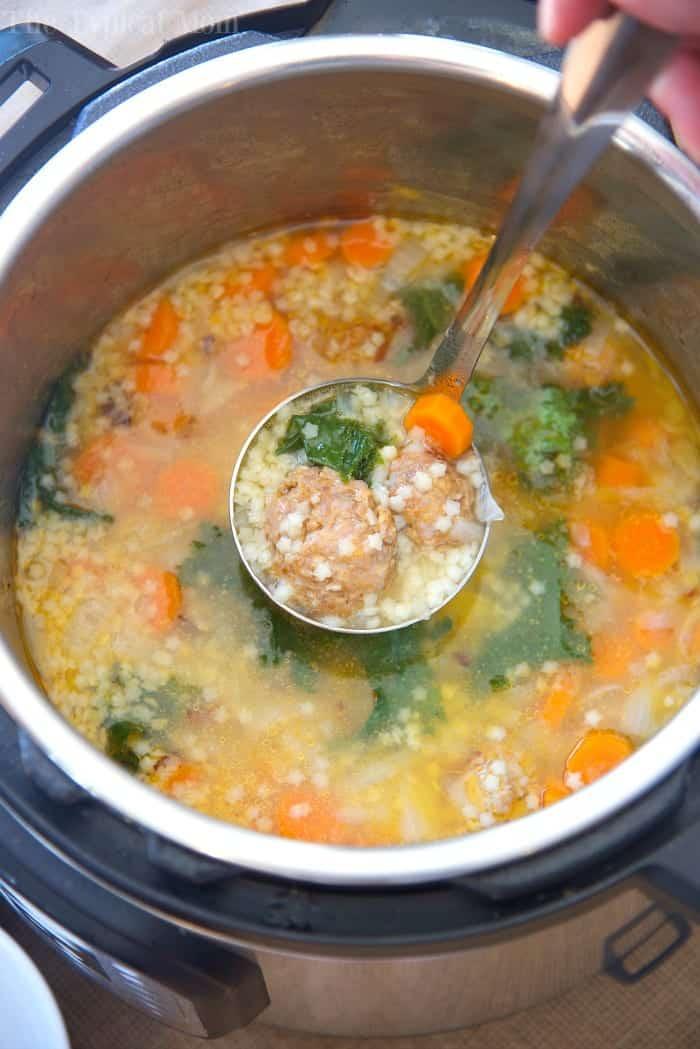 A ladle lifts meatball and vegetable soup from an Instant Pot, showing carrots, greens, and pasta—perfect inspiration for instant pot soup recipes.