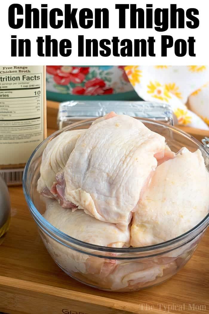 A glass bowl filled with bone-in raw chicken thighs is placed on a kitchen counter. Nearby are a carton of chicken broth and a pressure cooker. The text Instant Pot Chicken Thighs is written at the top of the image.