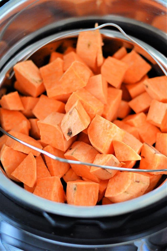 Cubes of sweet potatoes sit in a pressure cooker, ready for cooking. Perfectly prepared, these Instant Pot sweet potatoes promise a quick and delicious meal.