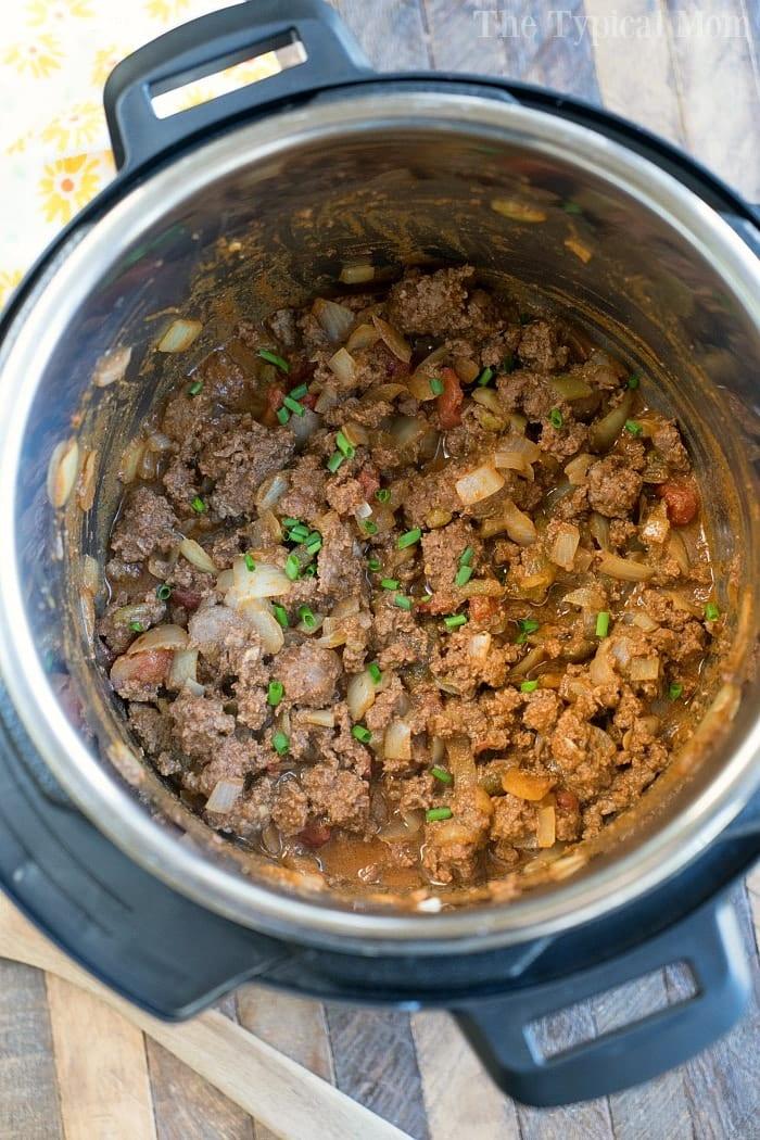Instant Pot taco meat with onions and tomatoes simmering to perfection, garnished with a sprinkle of fresh green onions.