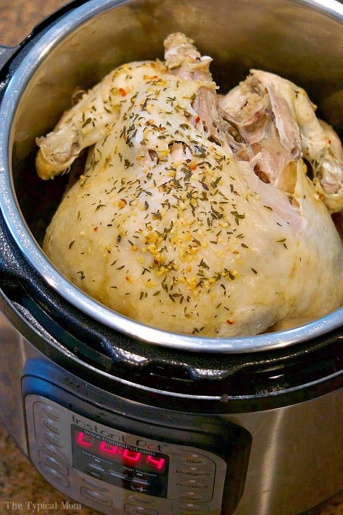 A whole chicken seasoned with herbs nestles in an Instant Pot, perfectly browned to golden perfection. The digital display proudly showcases the cooking details for this succulent Instant Pot whole chicken.