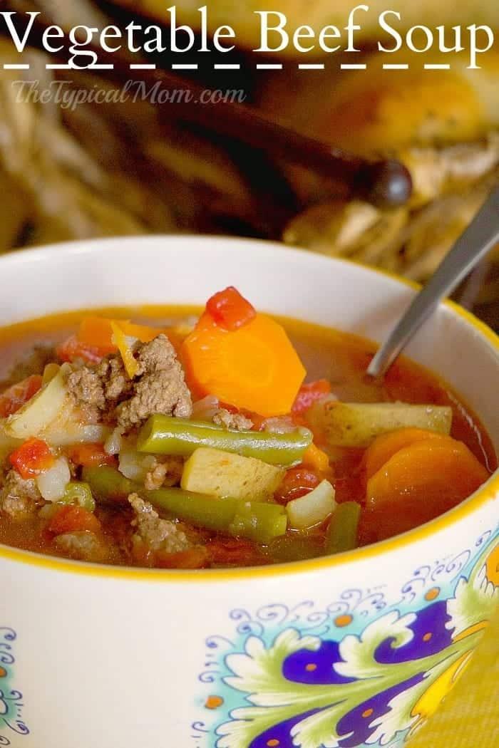 A bowl of vegetable beef soup with carrots, green beans, beef, and tomatoes sits with a spoon in the bowl—perfect inspiration for leftover meatloaf recipes.