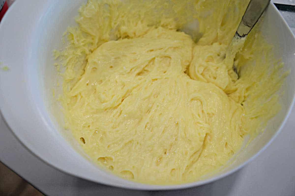 A white bowl filled with creamy yellow carnivore diet cake batter and a metal spoon partially dipped in.