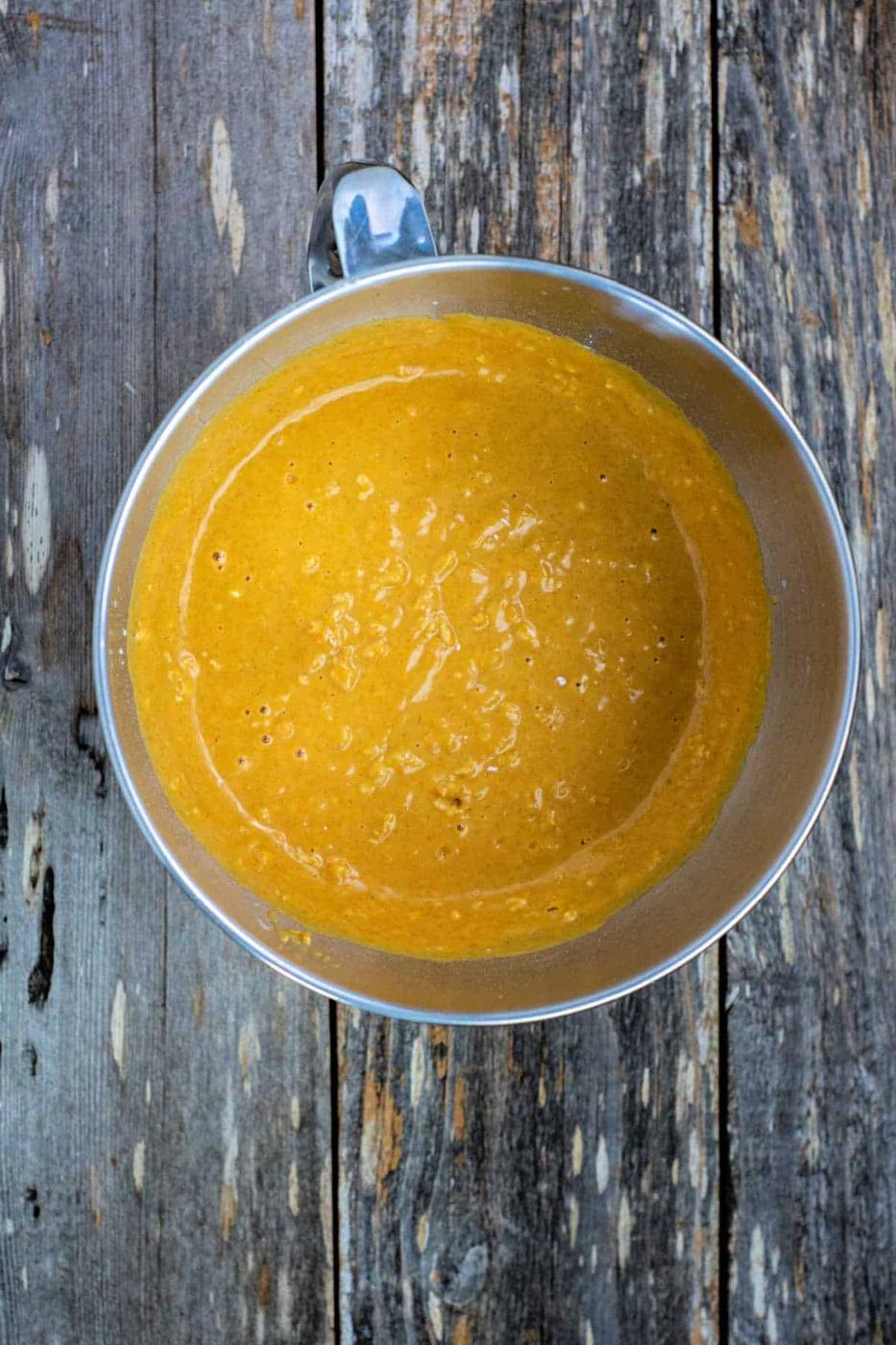 A bowl of maple pumpkin bread batter rests on a rustic wooden surface.