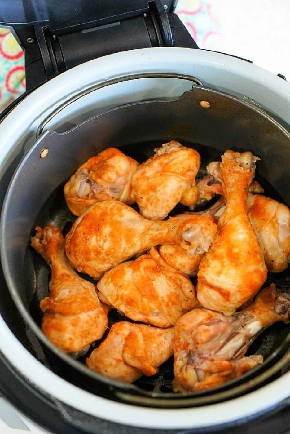 Chicken drumsticks with a golden-brown crust inside a Ninja Foodi air fryer basket.