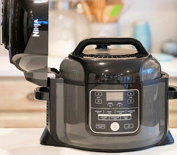 A black Ninja air fryer with its lid open sits on a kitchen counter, perfect for trying out your favorite Ninja pressure cooker recipes.