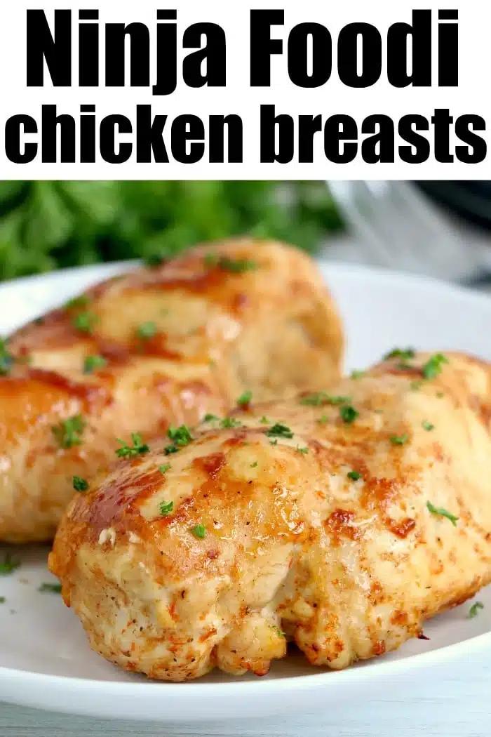 Two cooked chicken breasts on a white plate, garnished with chopped herbs, with text reading Ninja Foodi chicken breasts—a delicious choice for anyone seeking easy ninja pressure cooker recipes.