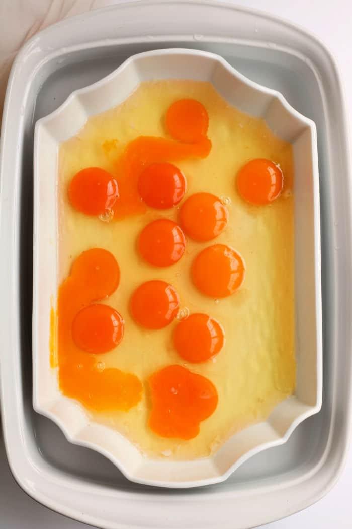 A white rectangular dish displays raw egg yolks and whites, showcasing an inviting simplicity reminiscent of no peel hard boiled eggs.