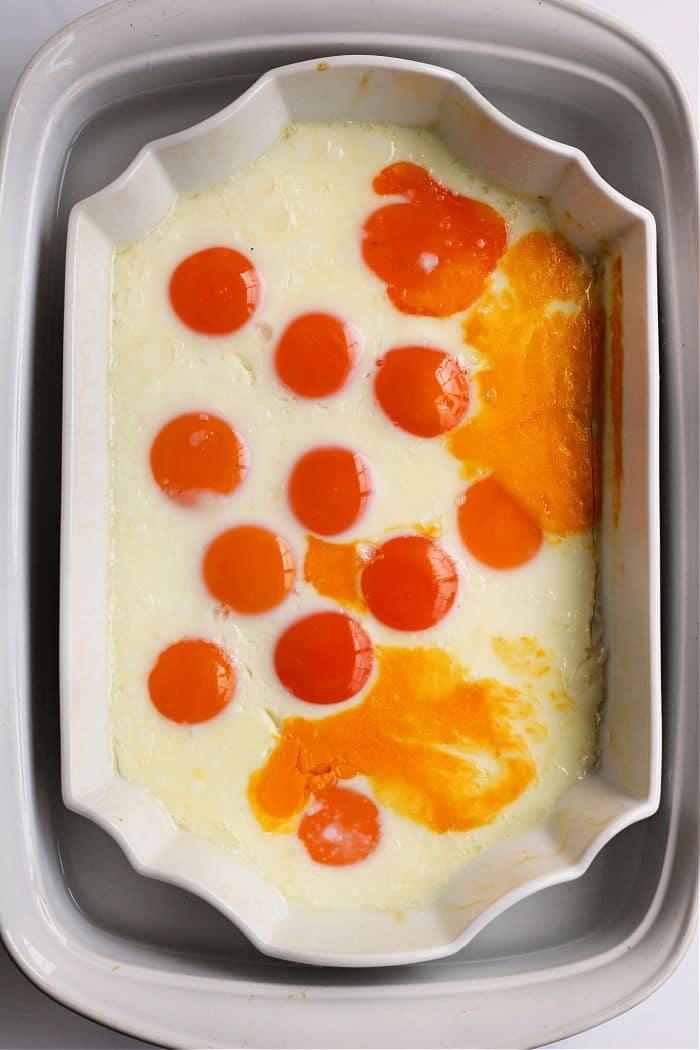 Baked eggs in a dish with vibrant yolks evenly distributed across the surface, resembling no peel hard boiled eggs.