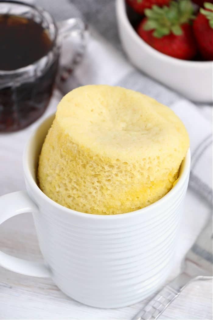 pancake in a white cup, paired perfectly with a bowl of strawberries and a steaming cup of coffee, brings to mind the comfort of a pancake in a mug.