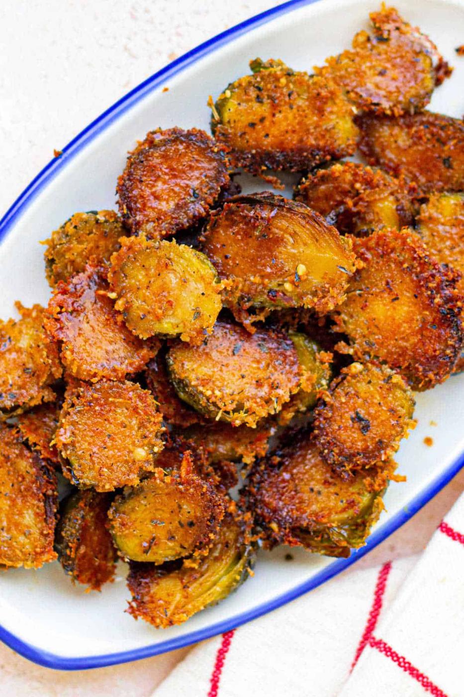Crispy, golden-brown parmesan brussels served on a white plate with a blue rim, reminiscent of Parmesan crusted Brussels sprouts.