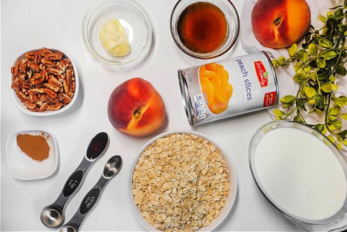 Ingredients for Peach Baked Oatmeal: peaches, pecans, oats, milk, butter, syrup, cinnamon, and measuring spoons.