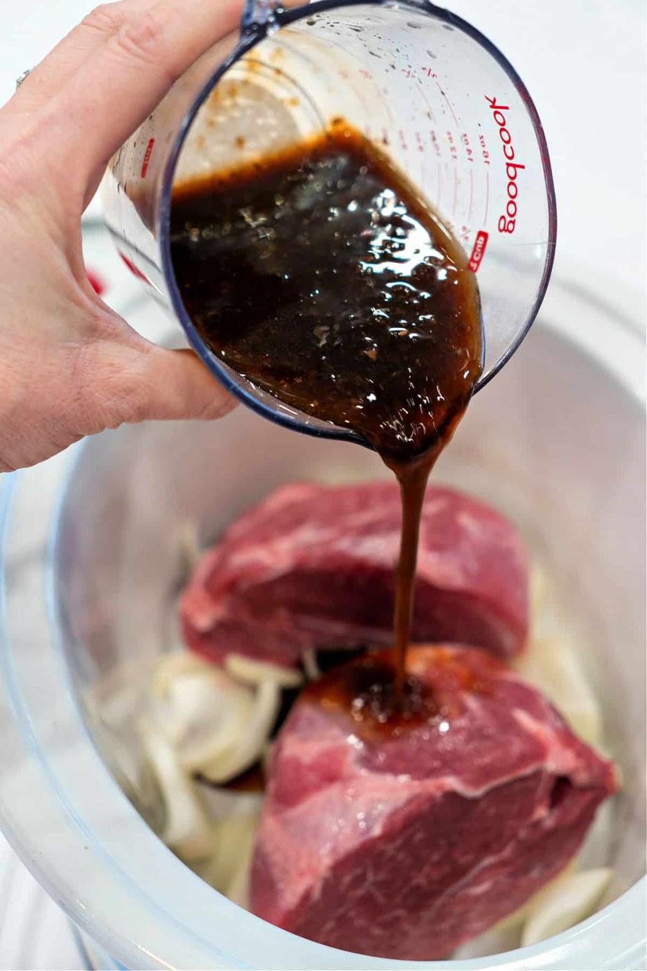 Pouring marinade over onions in a slow cooker, as if preparing a succulent pork picnic roast, infusing every layer with flavor.