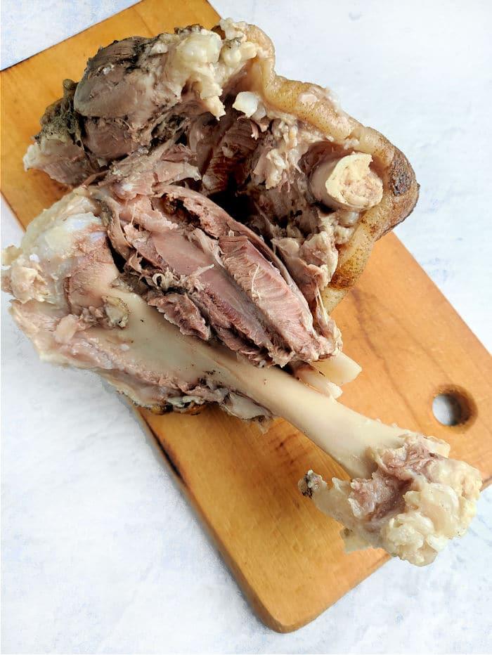 A sumptuous pork shank, bone and tender meat on display, rests elegantly on a wooden board.