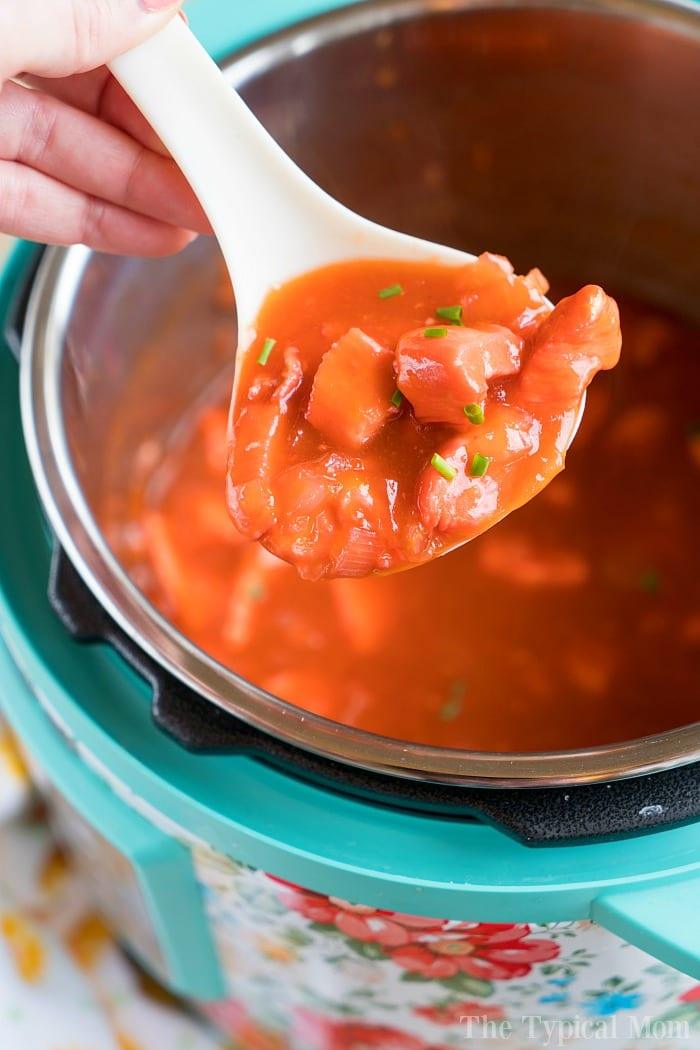 A spoonful of apricot chicken held over a pressure cooker, ready to delight your taste buds.