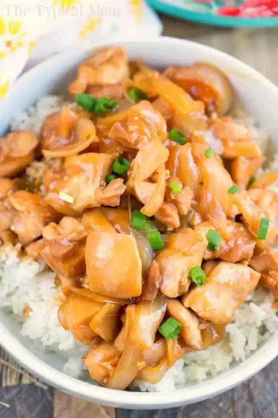 Bowl of hoisin chicken with chopped green onions served over white rice.