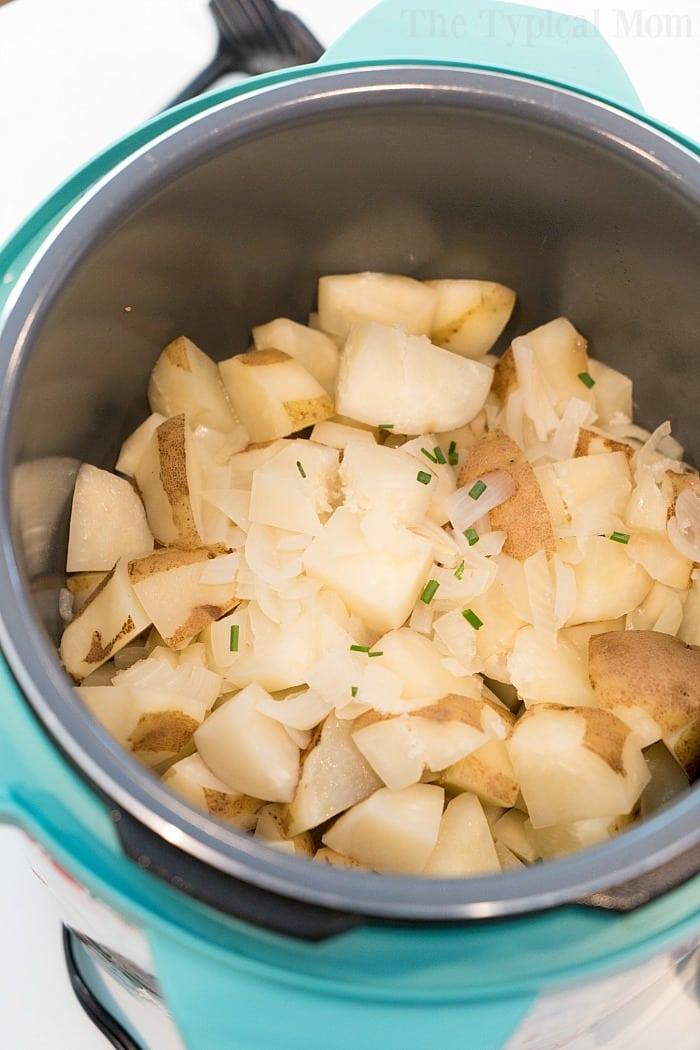 Chopped potatoes and onions gently cook in the teal slow cooker, creating a comforting aroma reminiscent of pressure cooker mashed potatoes.