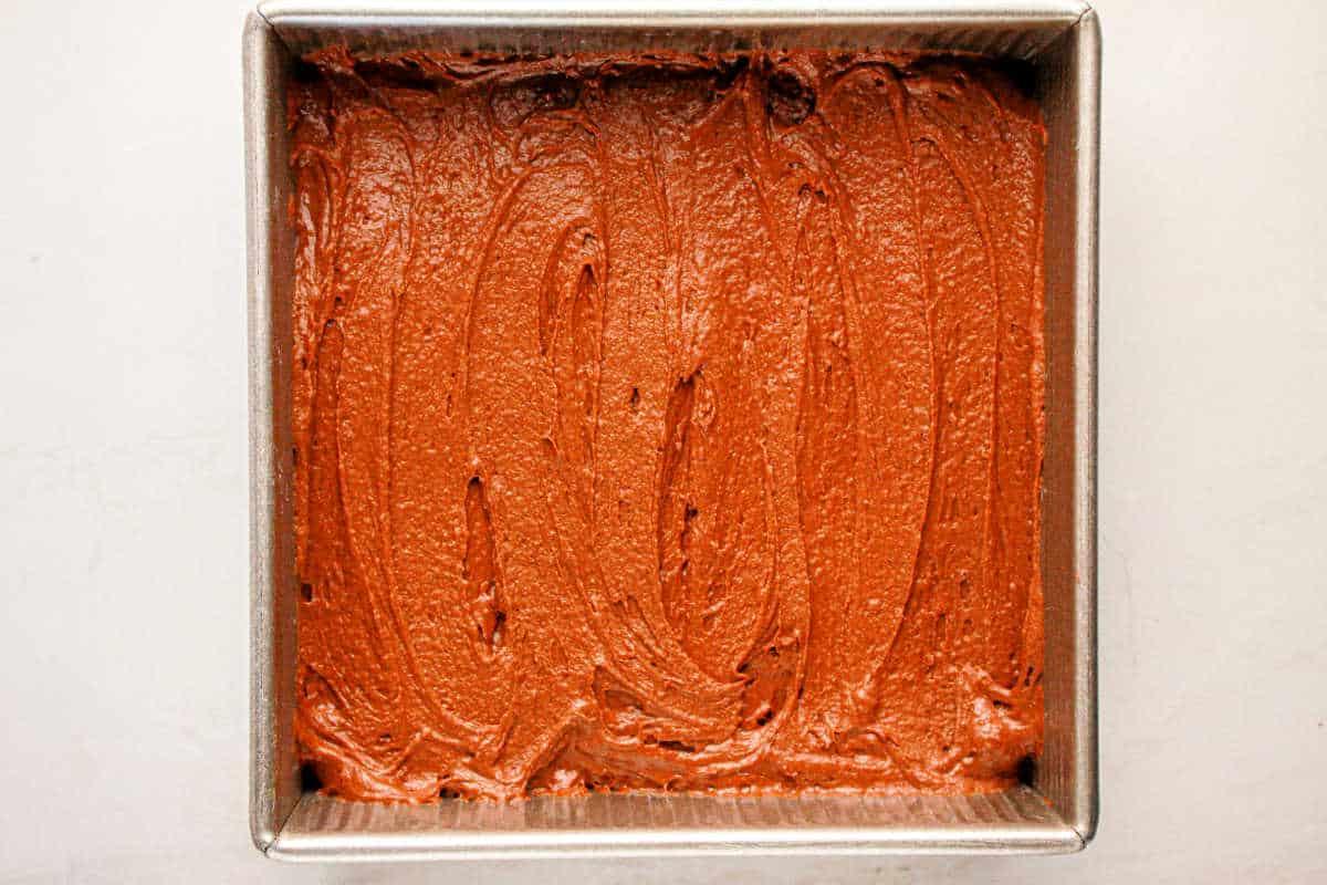 Protein-packed brownie batter spread evenly in a square metal baking pan.