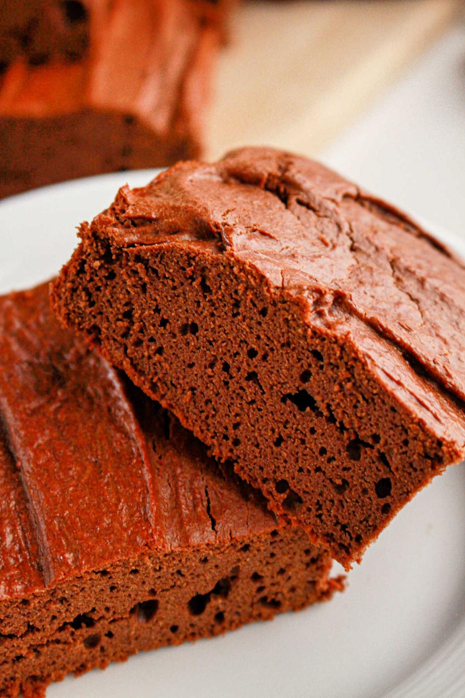 Close-up of two decadent slices of protein brownies on a white plate.