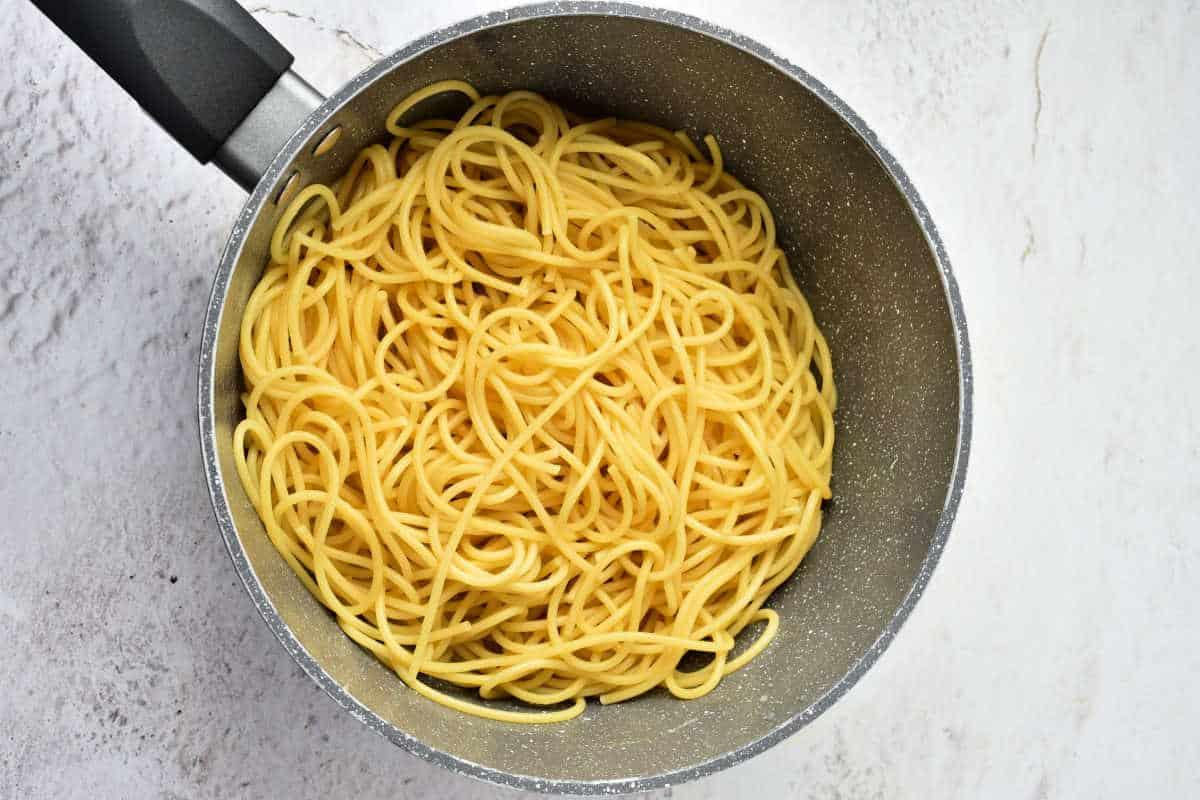 Cooked Pumpkin Spaghetti noodles in a gray pot on a light-colored countertop, viewed from above.