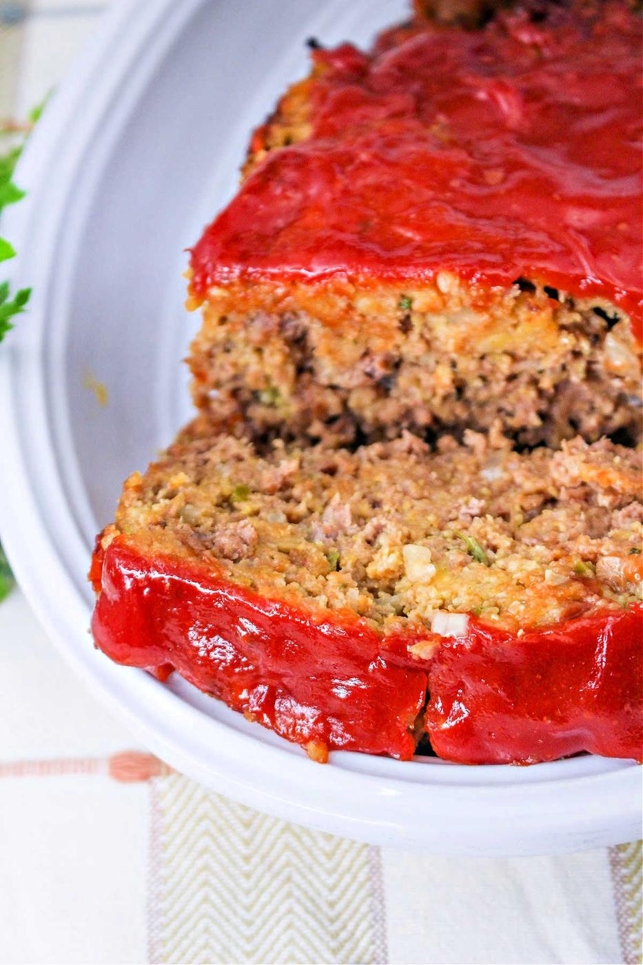 A sliced meatloaf with a thick layer of red sauce on top, served on a white plate—perfect for anyone looking for a quick meatloaf recipe.