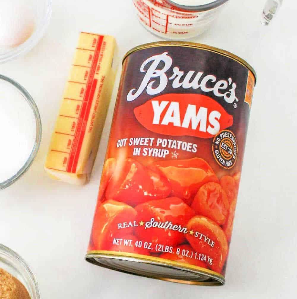 A can of Bruceâs Yams, labeled "Cut Sweet Potatoes in Syrup" and "Real Southern Style," perfect for a Recipe for Sweet Potato Pie with Sweetened Condensed Milk. The can is 40 ounces (2 lbs 8 oz / 1.134 kg). Nearby are a stick of butter, a measuring cup, and other cooking ingredients.