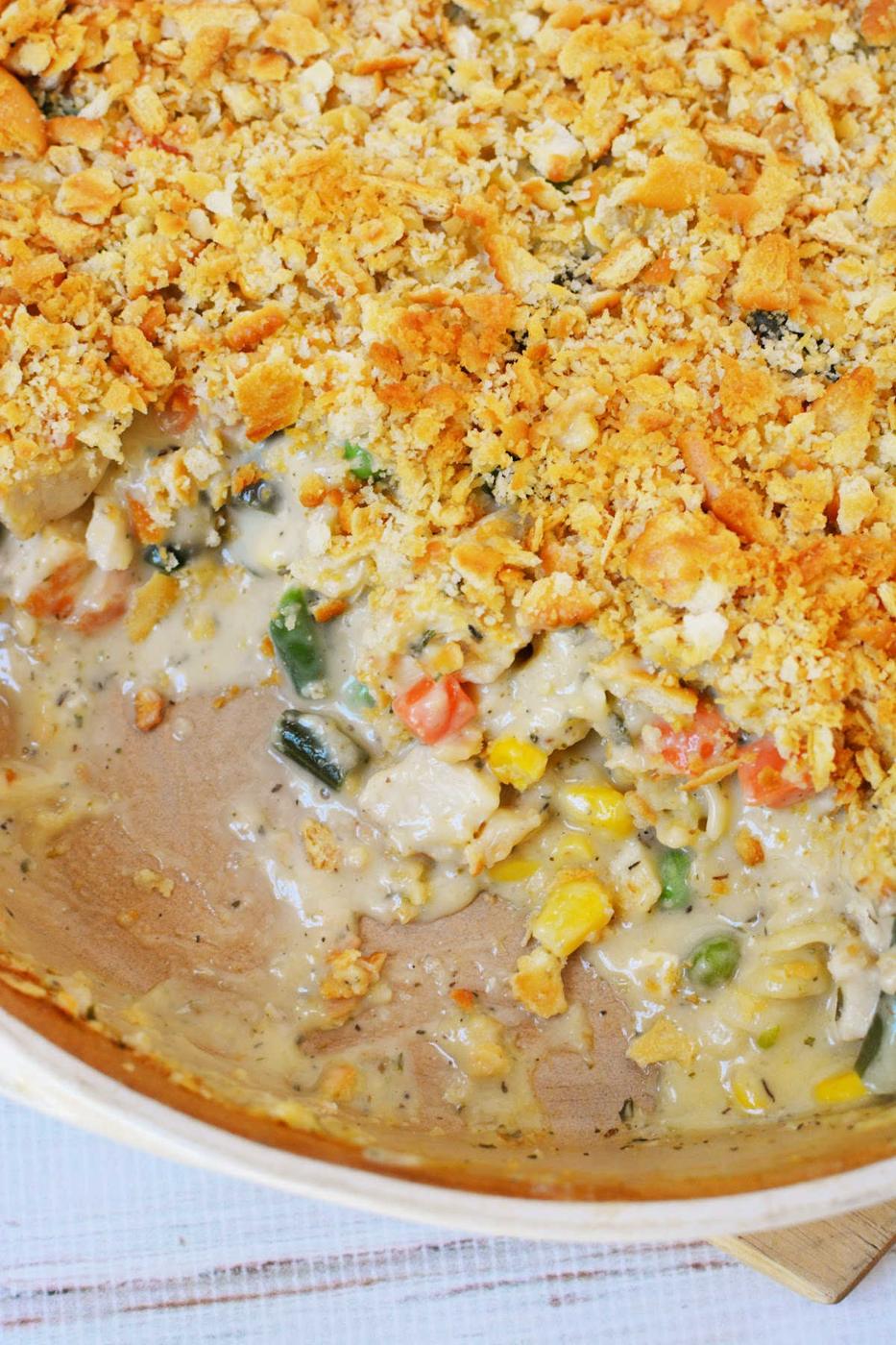 Creamy vegetable casserole with a golden Ritz cracker crumb topping, partially served to reveal the rich filling—similar in comfort to a classic Ritz Chicken Casserole.