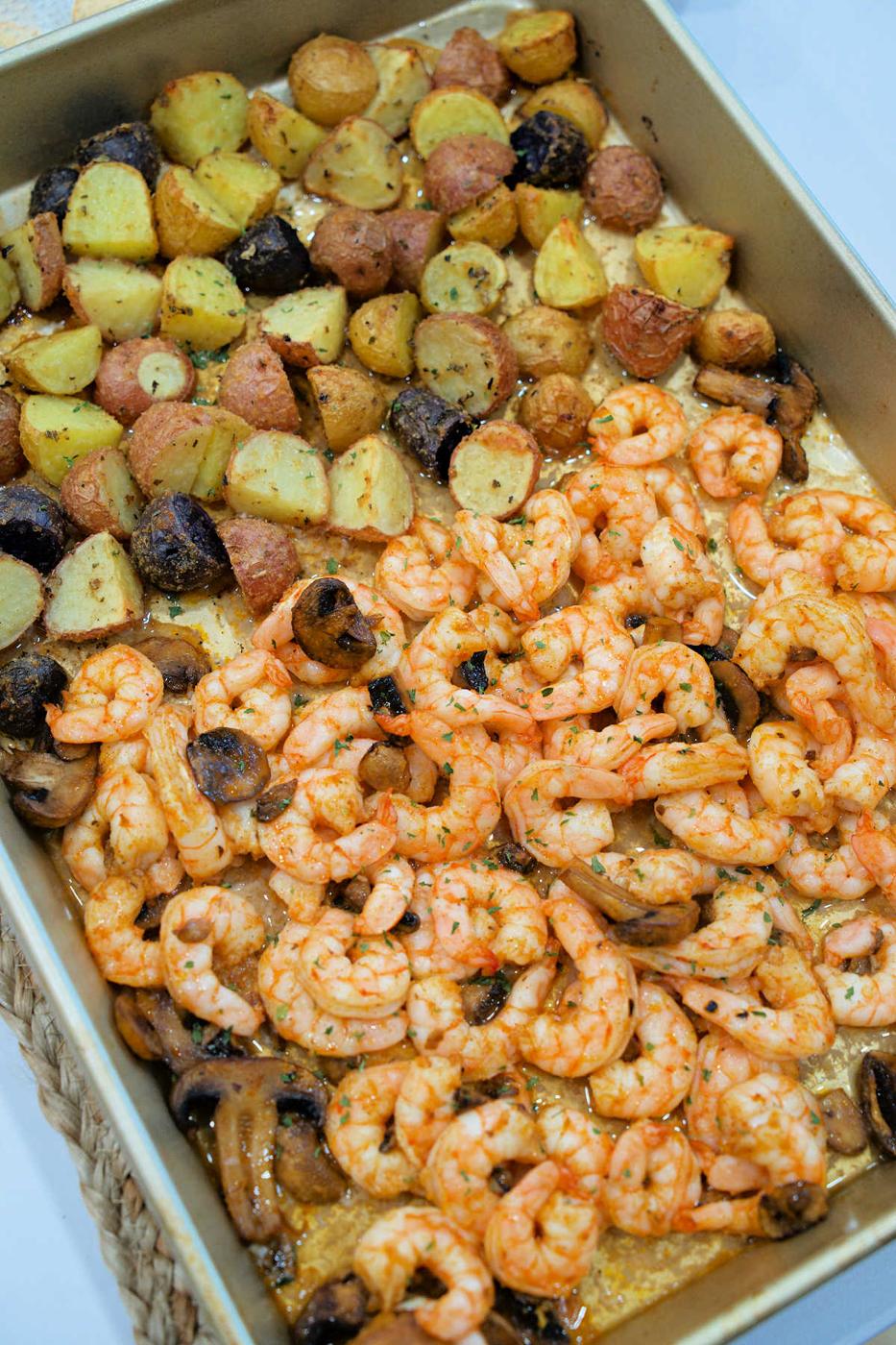 Roasted shrimp and potatoes, paired with savory mushrooms, all seasoned to perfection in a rectangular baking pan.