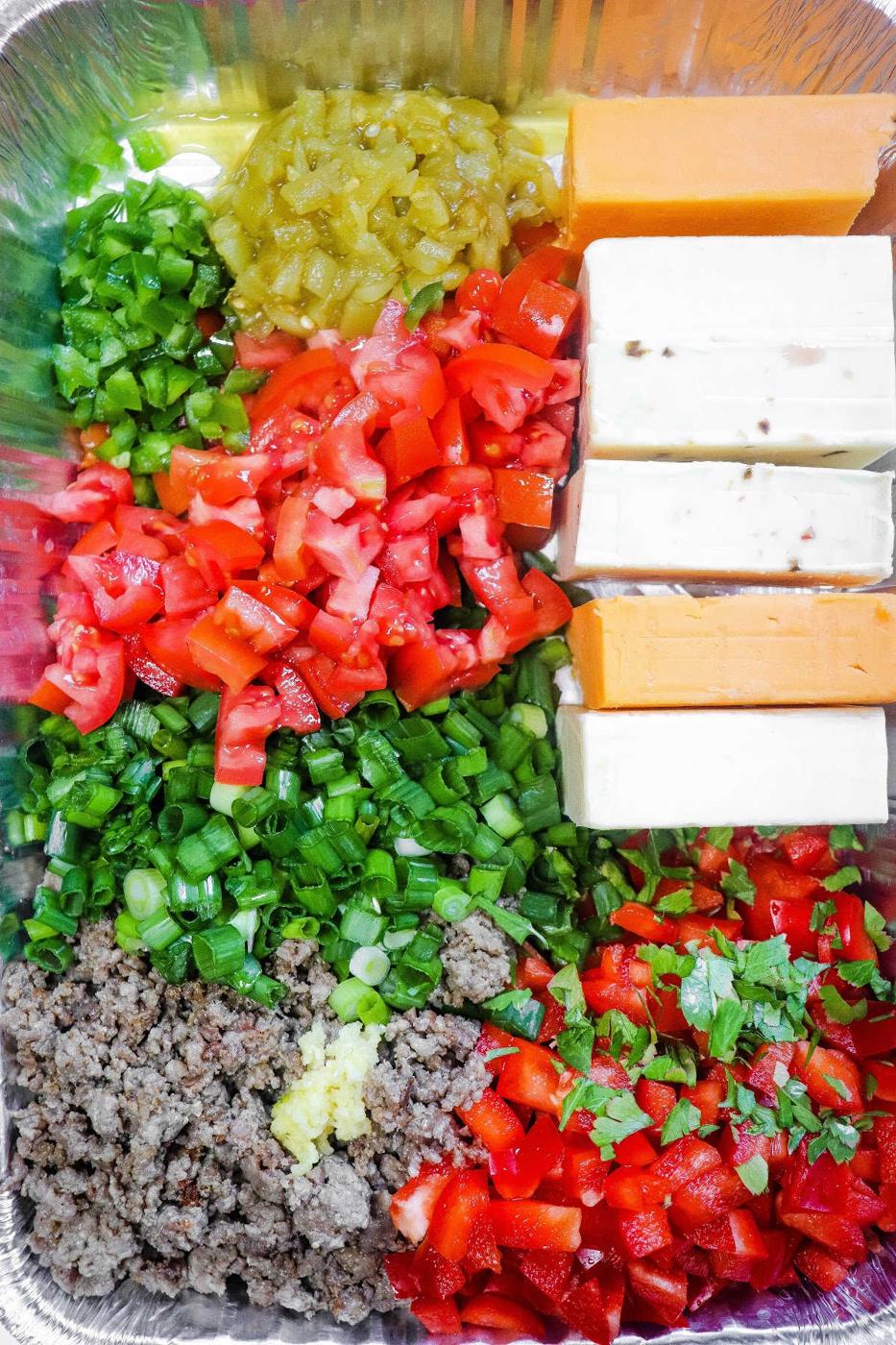 Chopped vegetables, cheeses, and cooked ground meat arranged in a tray for meal prep pair perfectly with a side of smoky queso dip.