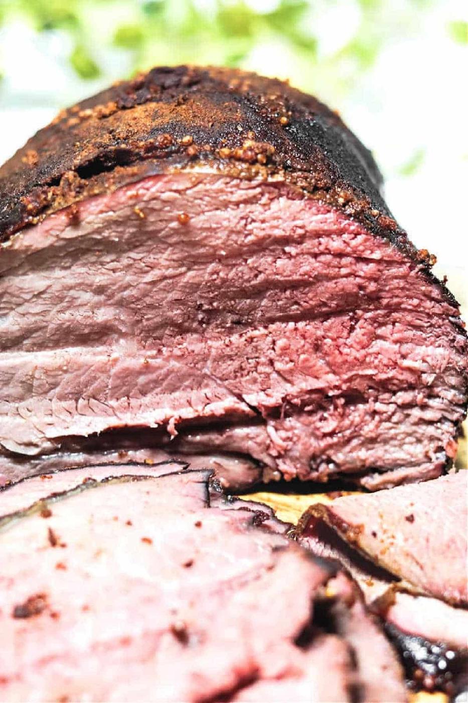 Sliced Smoked Sirloin Tip Roast displays a juicy interior and a dark, seasoned crust, just like classic smoked beef brisket.