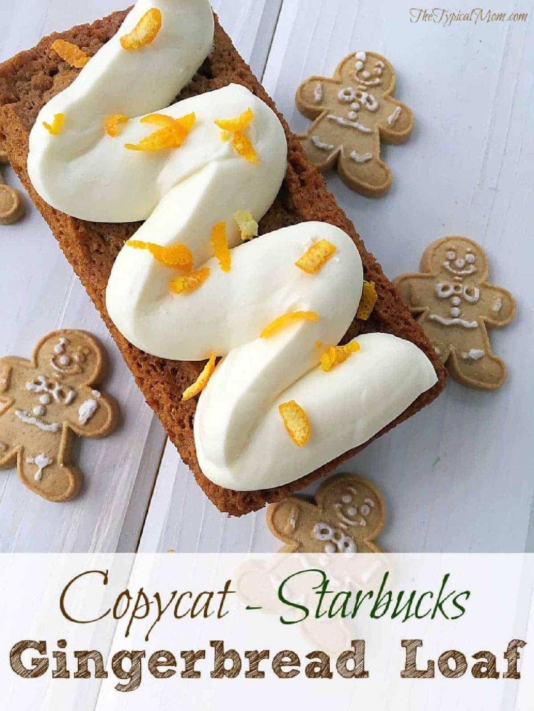 A Starbucks gingerbread loaf with white icing and orange zest, surrounded by gingerbread cookies on a white surface.
