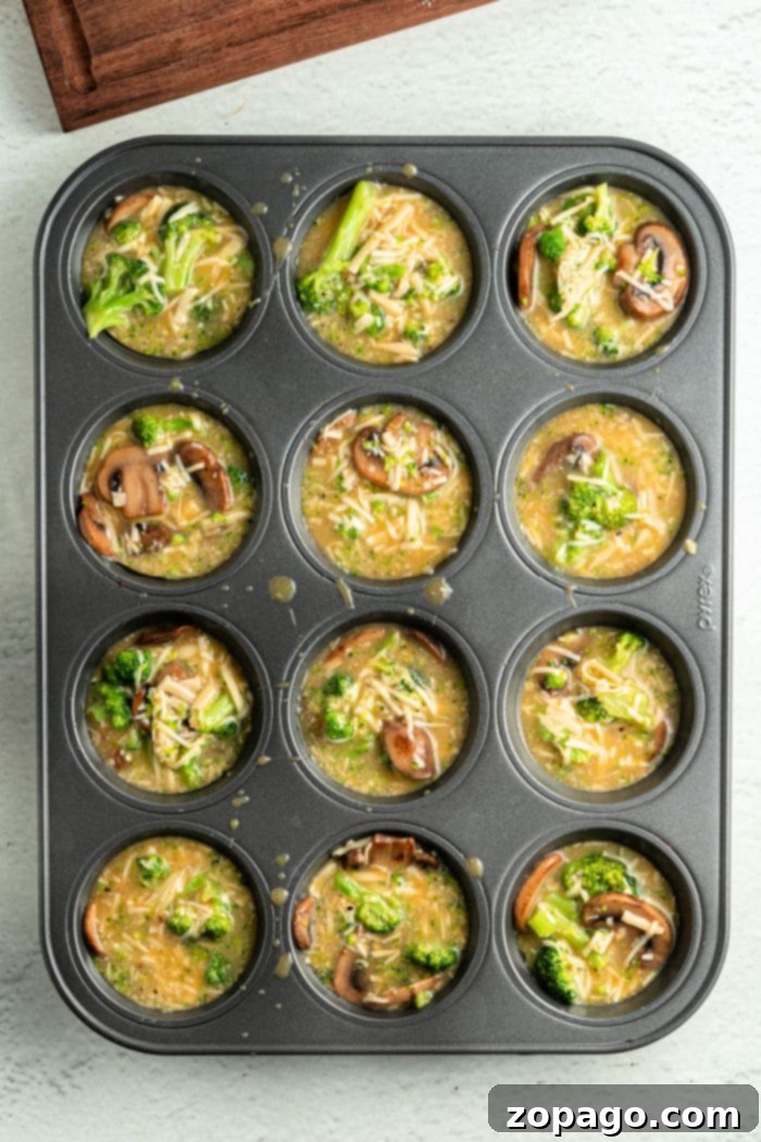Broccoli & Cheddar Egg Bake 6 A hand gently removing a crustless broccoli quiche from a muffin tin with a knife, highlighting ease of removal.