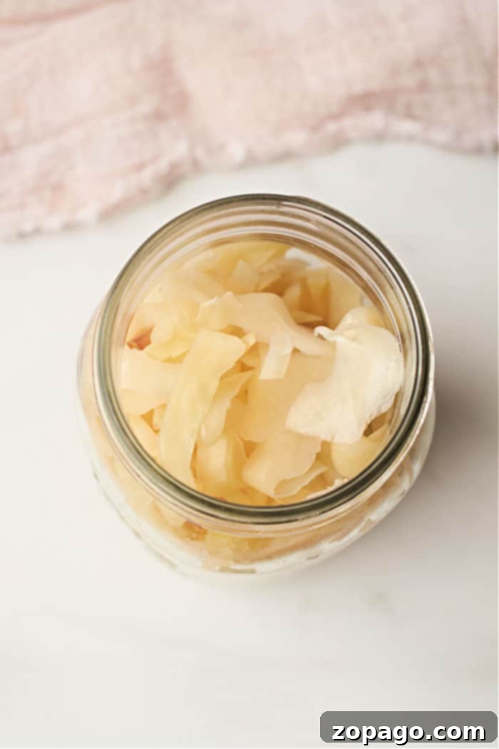 Whip Up Quick Sauerkraut 5 A glass jar filled with marinated cabbage rests on a light fabric background, reminiscent of the subtle simplicity of a quick sauerkraut recipe.
