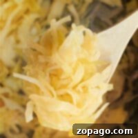 Whip Up Quick Sauerkraut 6 Close-up of sauerkraut on a wooden spoon above a pot filled with more sauerkraut, capturing the essence of a quick sauerkraut recipe.