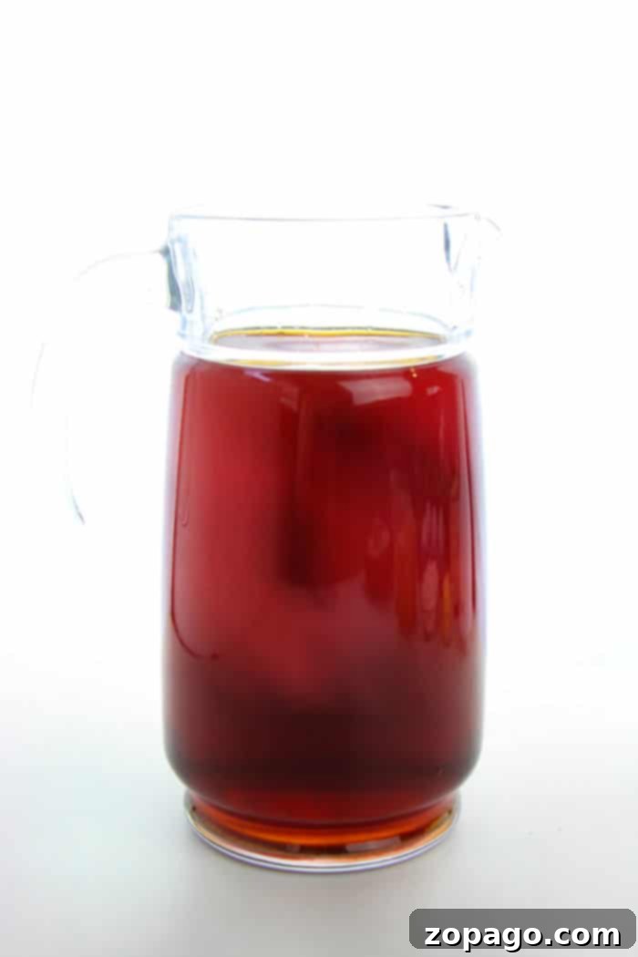 Sweet Berry Hibiscus Brew 5 A refreshing glass of homemade iced tea with lemon and mint leaves on a wooden table.