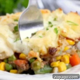 Hearty Slow Cooker Shepherd's Pie 6 A fork digs into the savory vegetable shepherd's pie, perfectly slow-cooked in a crockpot and topped with creamy mashed potatoes and melted cheese.
