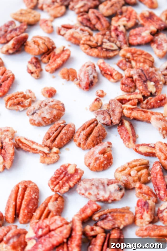 Sweet & Crunchy Pecans 5 A close-up of assorted candied pecans prepared on the stove, scattered on a white surface.