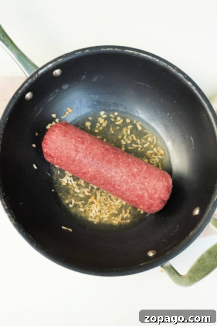 Mastering Frozen Ground Beef 5 A black frying pan filled with raw frozen ground beef and chopped onions sizzles, reminiscent of a guide on how to cook frozen ground beef.