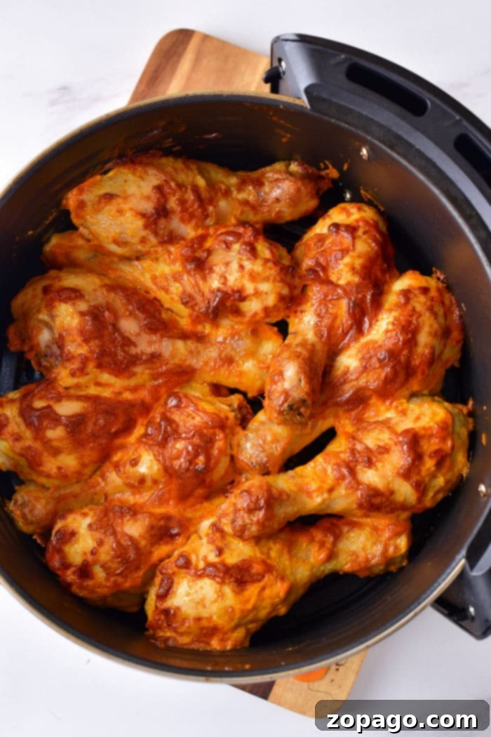 The Art of Boiling Chicken Legs 7 Baked chicken drumsticks coated in a rich sauce resting in a black baking dish on a wooden board, showcasing a delicious post-boiling preparation ready to be served.
