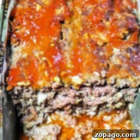 Juicy Meatloaf Without the Filler 6 Meatloaf without breadcrumbs, featuring a rich tomato glaze, in a pan, partially sliced to reveal its savory interior.