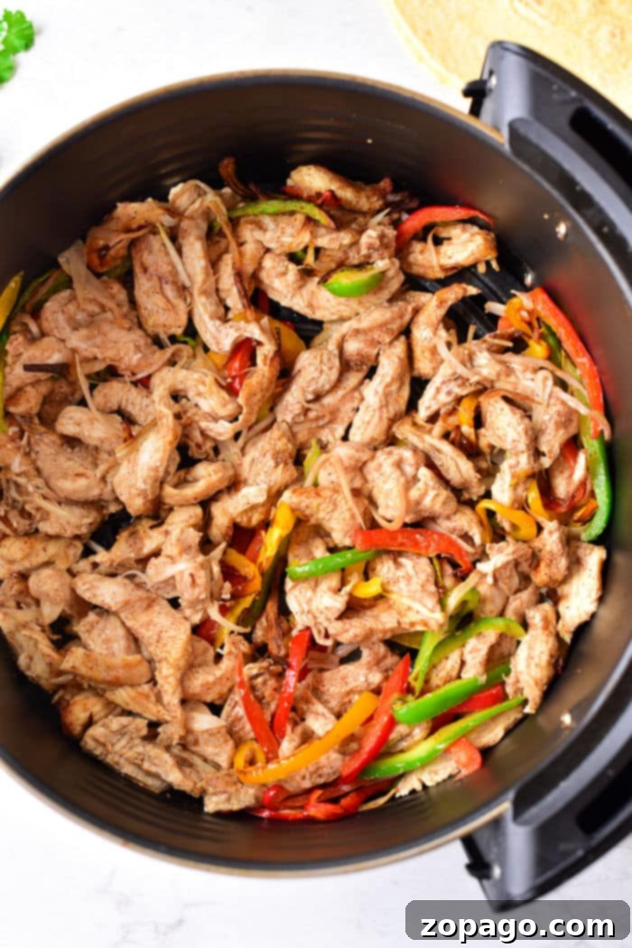 Sizzling Fajita Chicken Tacos 7 A sizzling pan filled with perfectly cooked chicken strips and vibrant red, green, and yellow bell peppers, forming the delectable base for Chicken Fajita Tacos.