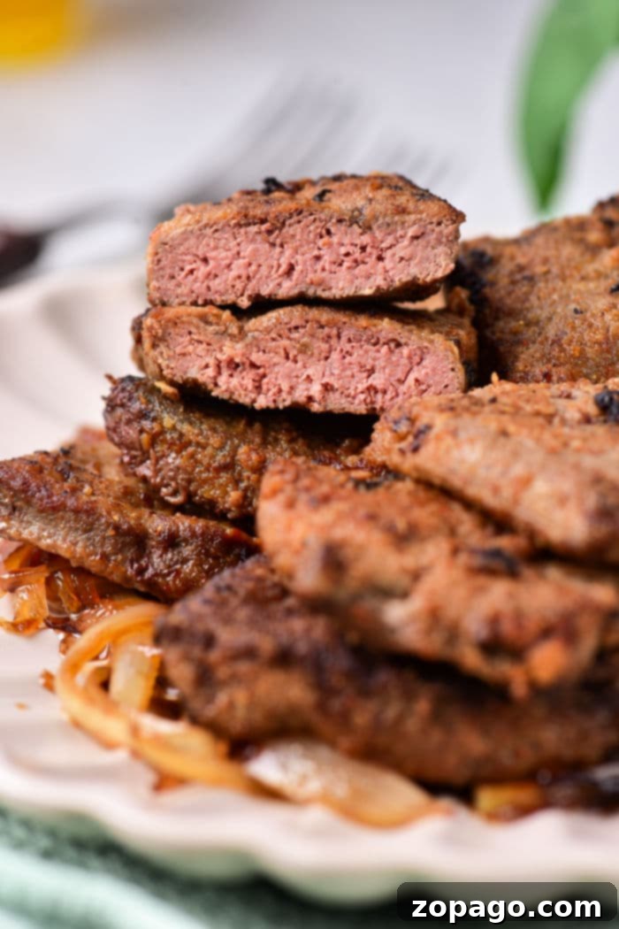 Delicious Pan-Seared Beef Liver 8 A close-up view of a plate featuring perfectly pan-fried beef liver topped with a generous portion of sweet caramelized onions, ready to be enjoyed.