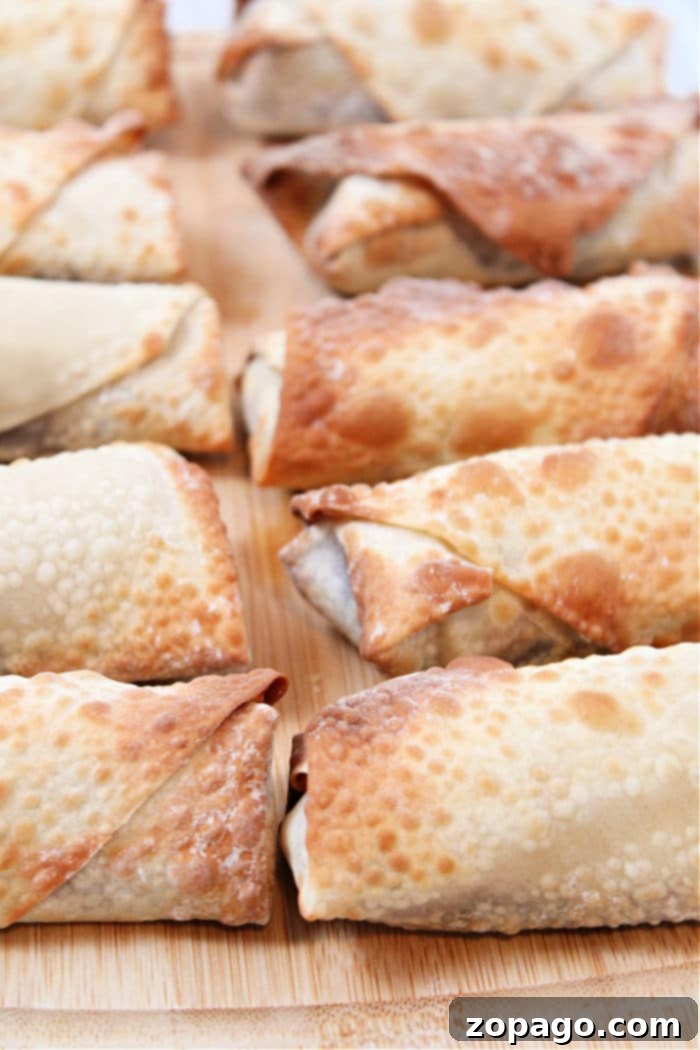Crispy Air Fryer Apple Pie Egg Rolls 6 Crispy Air Fryer Apple Pie Egg Rolls stacked on a plate.