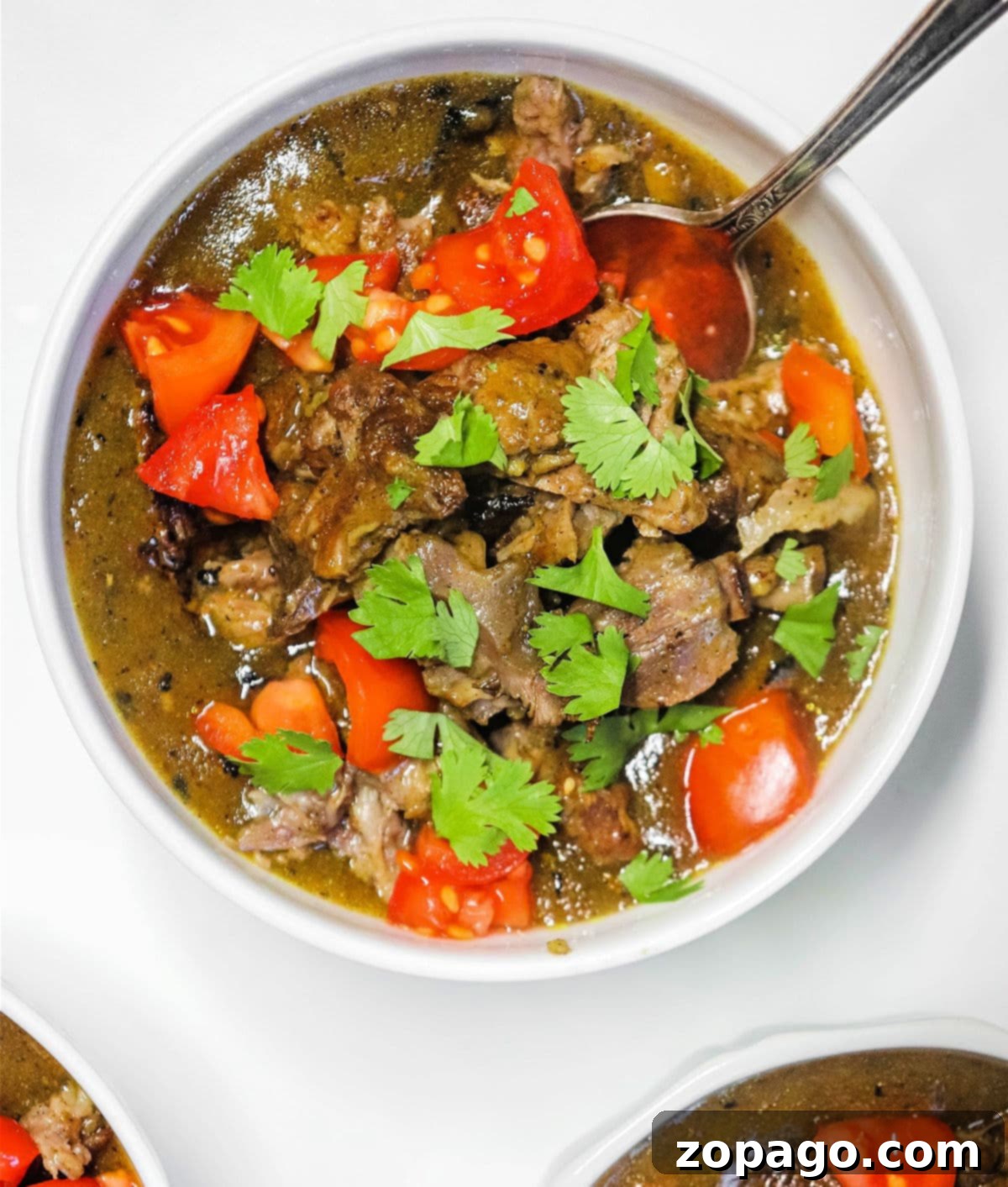 Velvet Oxtail Curry 7 Overhead view of several bowls of oxtail curry, garnished with fresh herbs, prepared for a family meal or gathering.
