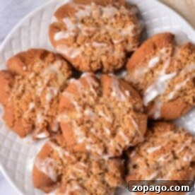 A plate of coffee cake cookies drizzled with white icing sits invitingly on a textured white plate.
