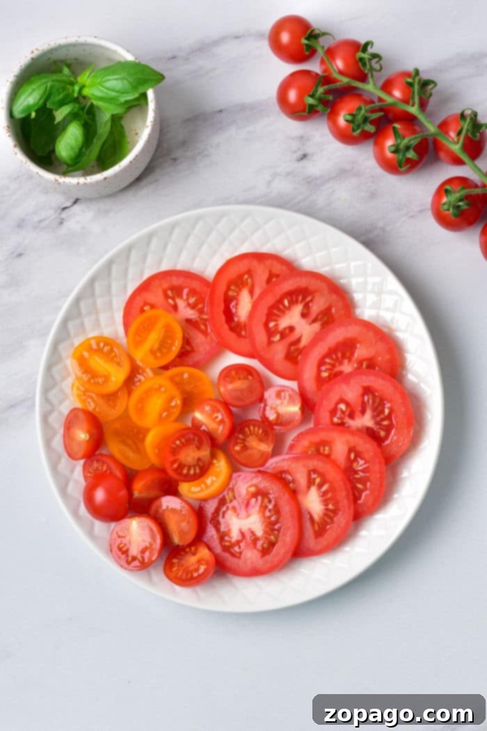 Burrata Caprese Nasıl Yapılır? 3 A beautifully composed plate of sliced red and yellow heirloom tomatoes, perfectly paired with a creamy burrata and garnished with fresh basil, showcasing a delightful Caprese.