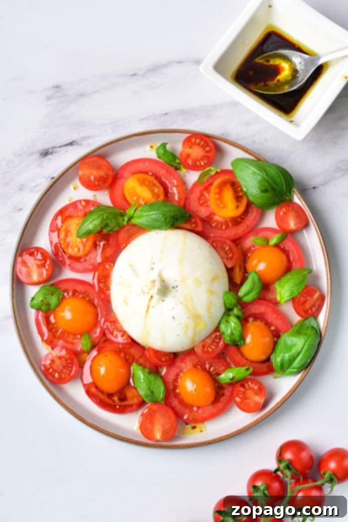 Burrata Caprese Nasıl Yapılır? 5 A close-up shot of Burrata Caprese showing the creamy texture of the cheese, accompanied by juicy tomatoes and basil, perfectly arranged on a serving plate.