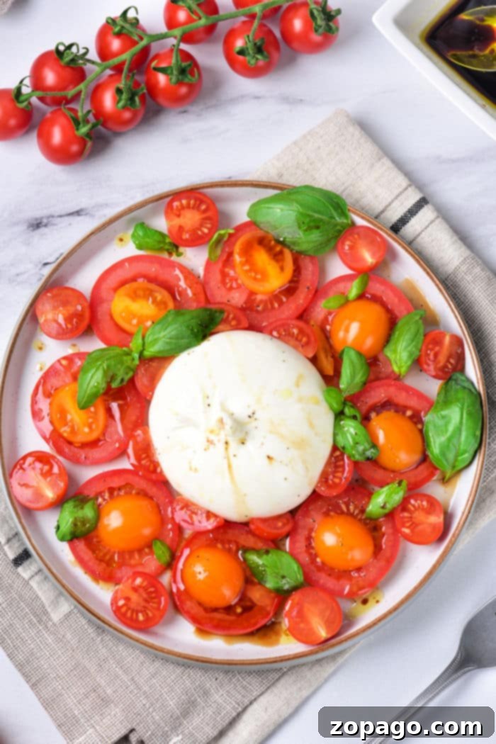 Burrata Caprese Nasıl Yapılır? 6 A close-up of a refreshing Burrata Caprese salad, featuring a whole burrata, colorful heirloom tomatoes, and fresh basil leaves, drizzled with balsamic glaze.